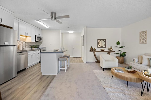 kitchen with white cabinets, a kitchen bar, stainless steel appliances, and light hardwood / wood-style floors