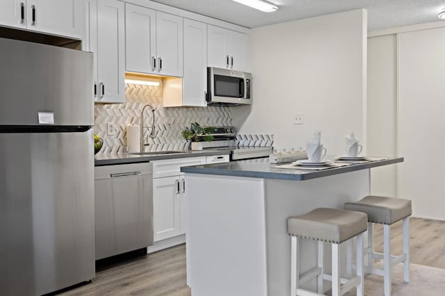 kitchen featuring sink, white cabinetry, stainless steel appliances, and light hardwood / wood-style flooring