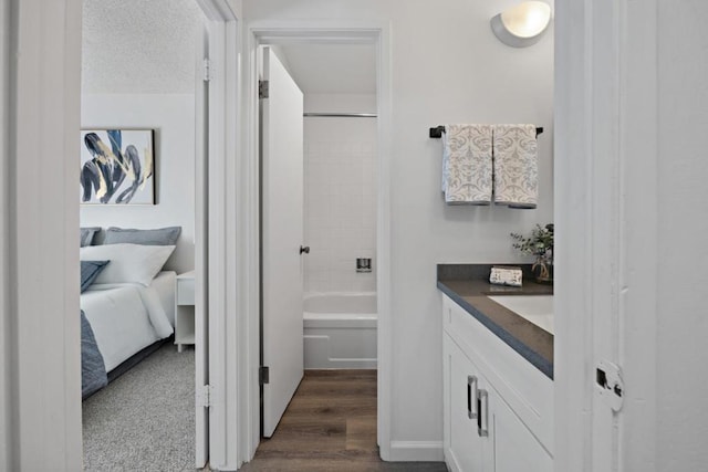 bathroom with hardwood / wood-style floors, vanity, a textured ceiling, and shower / washtub combination