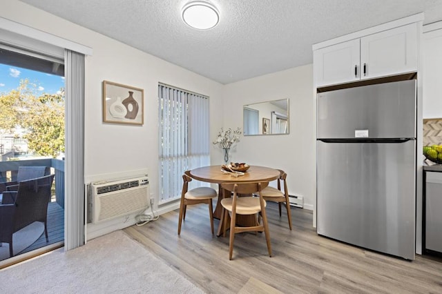 dining room with a wall mounted air conditioner, a textured ceiling, and light wood-type flooring