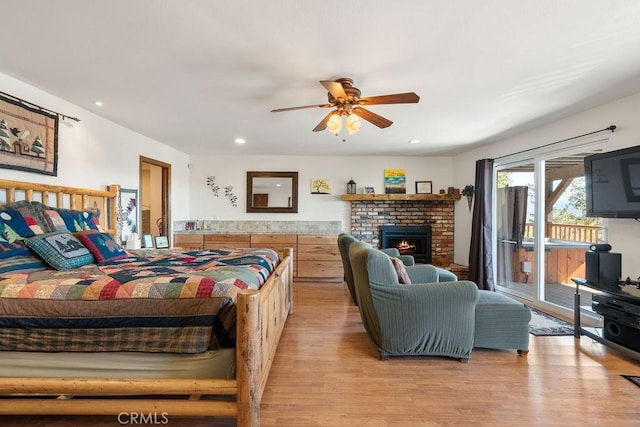 bedroom with ceiling fan, light hardwood / wood-style floors, access to outside, and a brick fireplace