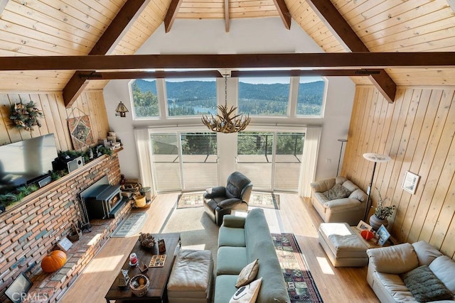 living room with plenty of natural light, a wood stove, high vaulted ceiling, and light hardwood / wood-style flooring