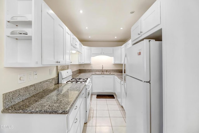 kitchen with white appliances, stone counters, sink, light tile patterned floors, and white cabinetry