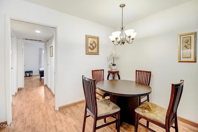 dining space featuring light hardwood / wood-style floors and an inviting chandelier