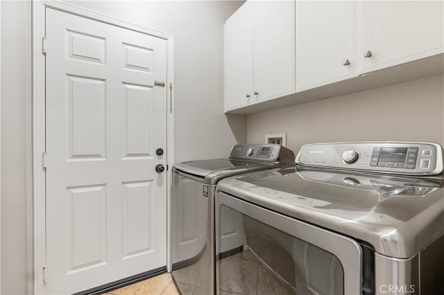 clothes washing area featuring cabinets, light tile patterned flooring, and washer and dryer