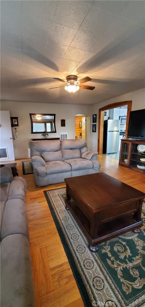 living room featuring ceiling fan, visible vents, and wood finished floors