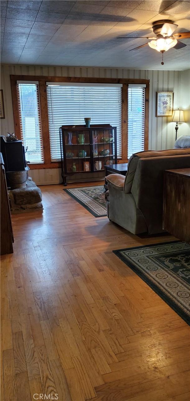 living room featuring hardwood / wood-style flooring, ceiling fan, and wooden walls