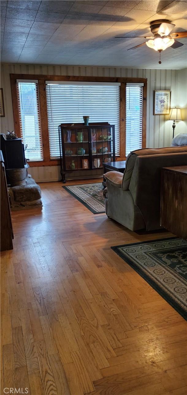 living room with a ceiling fan, plenty of natural light, and wood finished floors