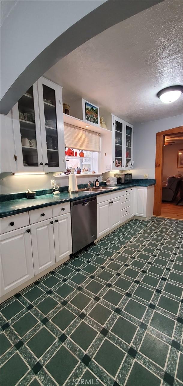 kitchen featuring white cabinets, dishwasher, sink, and a textured ceiling