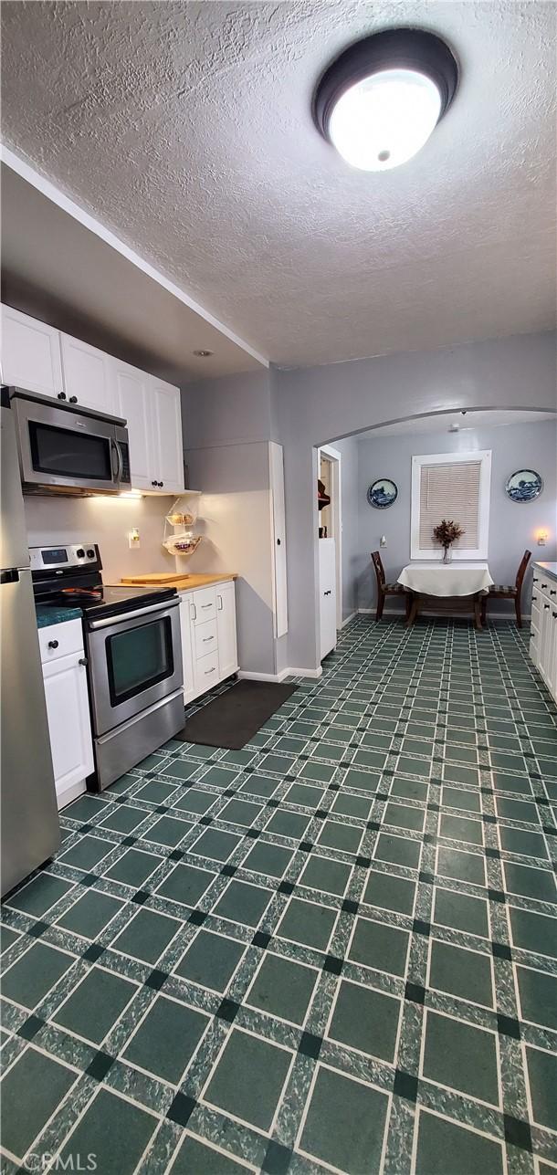 kitchen with white cabinets, a textured ceiling, and appliances with stainless steel finishes