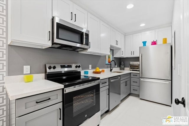 kitchen with white cabinets, gray cabinetry, sink, and appliances with stainless steel finishes