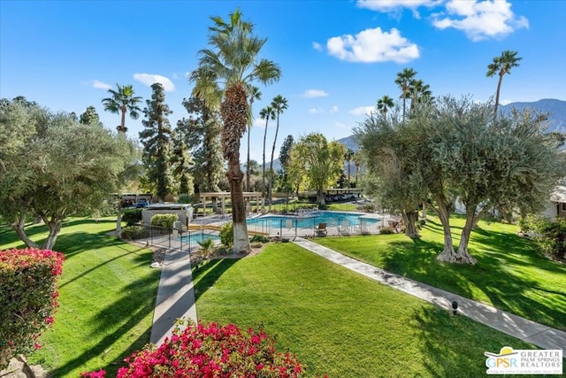 view of property's community with a lawn, a mountain view, and a swimming pool