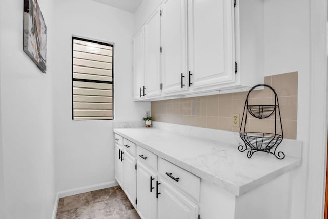 bar featuring white cabinets, backsplash, and light stone countertops