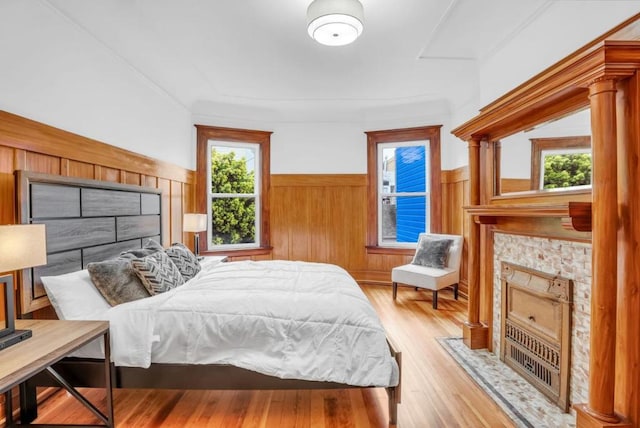 bedroom with light hardwood / wood-style flooring, a tile fireplace, and multiple windows