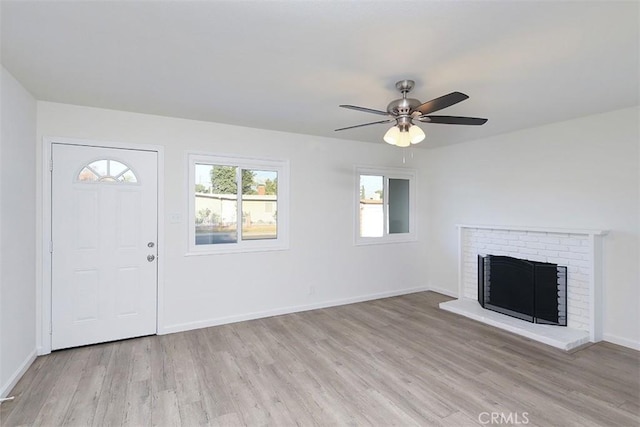 unfurnished living room with light wood-type flooring, ceiling fan, and a fireplace