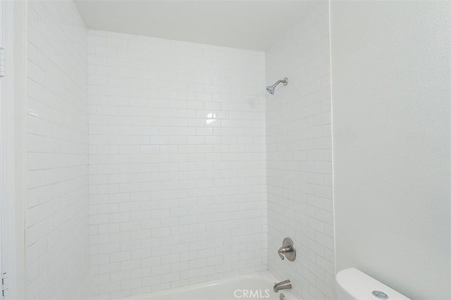 bathroom with toilet and tiled shower / bath