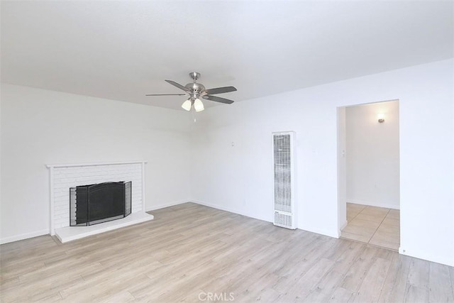 unfurnished living room with ceiling fan, light hardwood / wood-style floors, and a brick fireplace