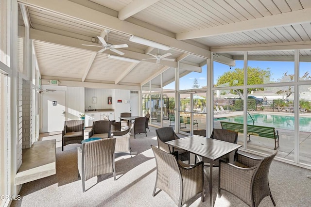 sunroom / solarium featuring a wealth of natural light, ceiling fan, and lofted ceiling with beams