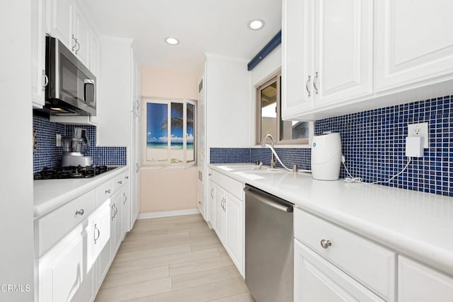 kitchen featuring backsplash, white cabinets, sink, light hardwood / wood-style floors, and stainless steel appliances