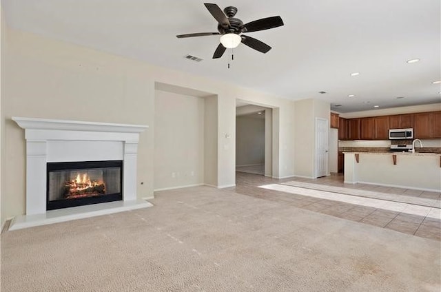 unfurnished living room featuring light colored carpet and ceiling fan