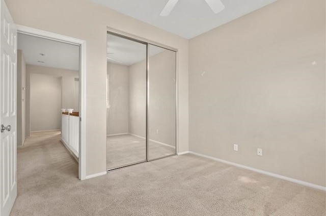 unfurnished bedroom with light carpet, a closet, and ceiling fan