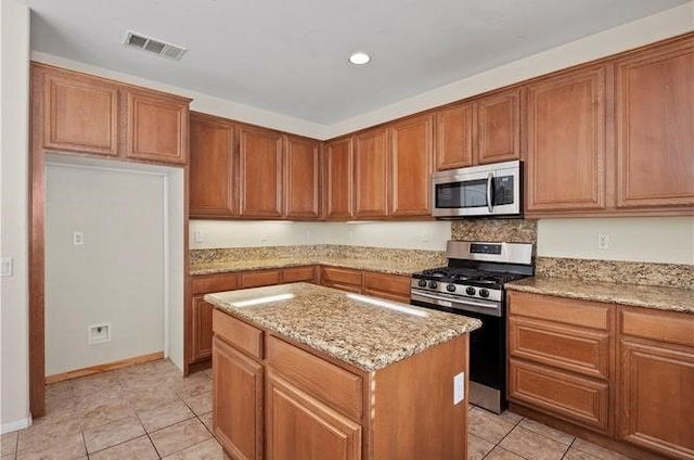 kitchen featuring a center island, light tile patterned floors, light stone countertops, and appliances with stainless steel finishes