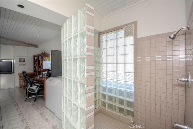 bathroom featuring tile patterned floors, vaulted ceiling, tile walls, walk in shower, and washer / clothes dryer