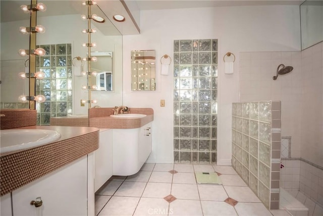 bathroom with tile patterned flooring, a tile shower, and sink