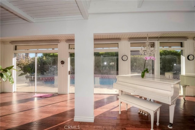 miscellaneous room featuring hardwood / wood-style flooring, plenty of natural light, beam ceiling, and an inviting chandelier