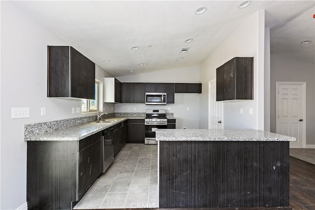 kitchen featuring lofted ceiling, sink, light wood-type flooring, appliances with stainless steel finishes, and a kitchen island