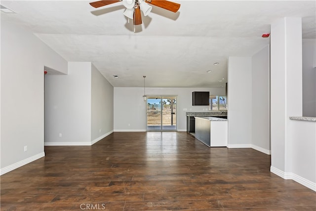 unfurnished living room featuring ceiling fan and dark wood-type flooring