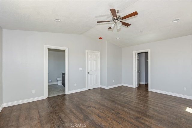 unfurnished bedroom with connected bathroom, dark hardwood / wood-style floors, vaulted ceiling, and ceiling fan