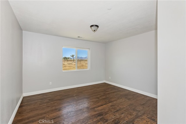 empty room featuring a textured ceiling and dark hardwood / wood-style flooring