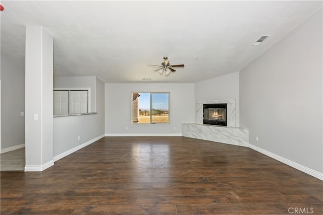 unfurnished living room with a high end fireplace, dark hardwood / wood-style floors, and ceiling fan