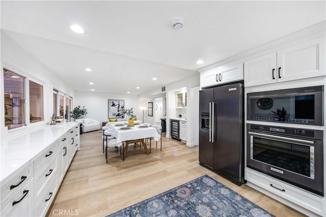 kitchen featuring beverage cooler, light stone counters, light hardwood / wood-style flooring, white cabinets, and appliances with stainless steel finishes