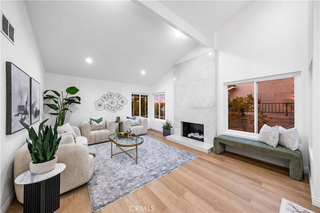 living room featuring hardwood / wood-style floors, a large fireplace, high vaulted ceiling, and beam ceiling