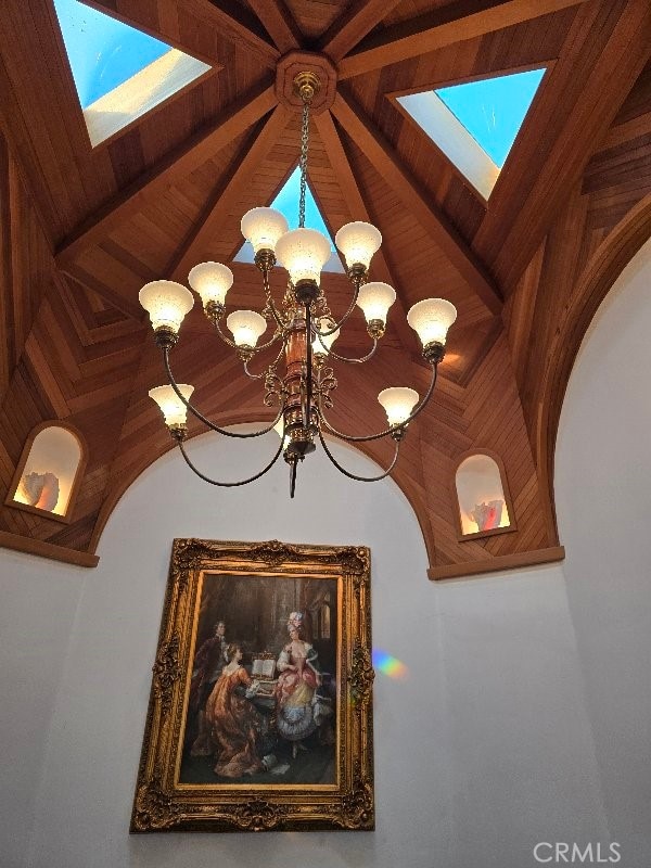 interior details featuring beamed ceiling, an inviting chandelier, wooden ceiling, and a skylight