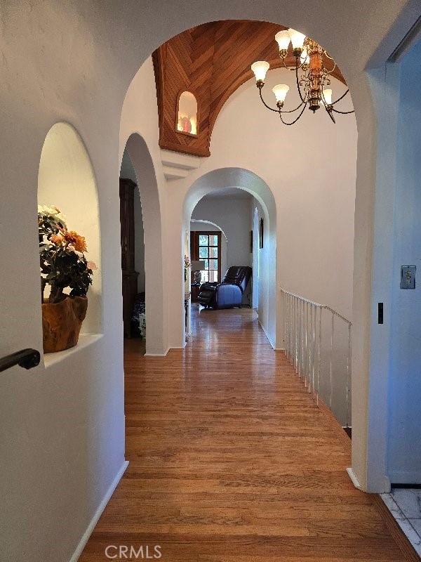 hall with hardwood / wood-style floors and a notable chandelier