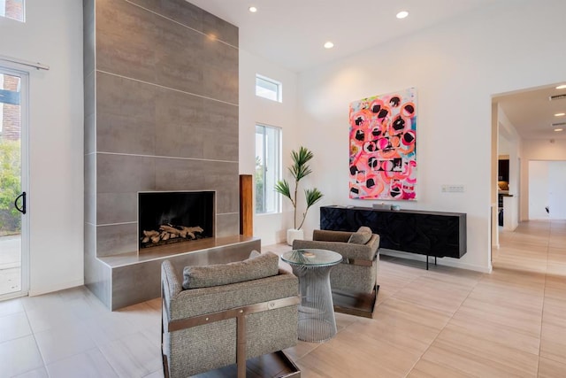 tiled living room with a towering ceiling and a tiled fireplace