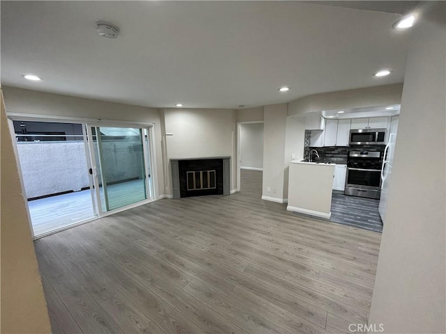 unfurnished living room with sink and light hardwood / wood-style floors