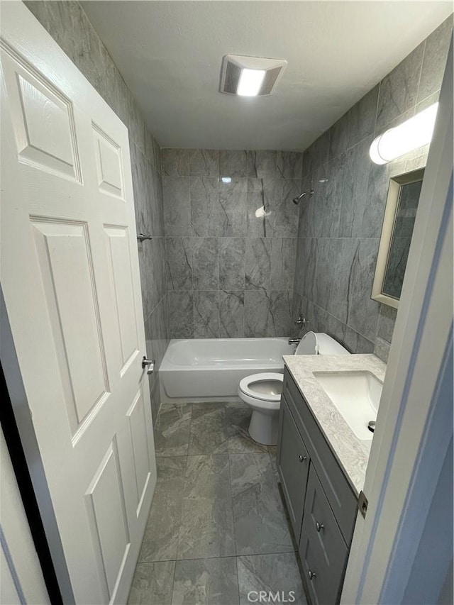 full bathroom with tiled shower / bath combo, toilet, tile walls, and vanity