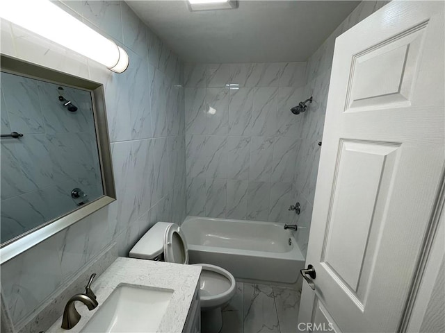 full bathroom with vanity, toilet, tiled shower / bath, and tile walls