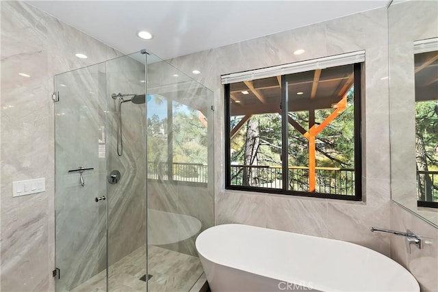 bathroom with separate shower and tub, a wealth of natural light, and tile walls