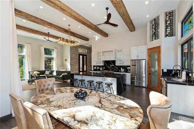 dining room with dark hardwood / wood-style flooring, beamed ceiling, ceiling fan with notable chandelier, and sink