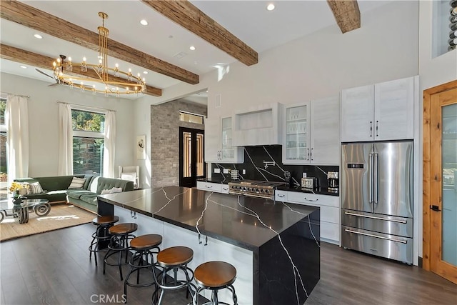 kitchen with beam ceiling, a center island, dark hardwood / wood-style flooring, high quality appliances, and a breakfast bar