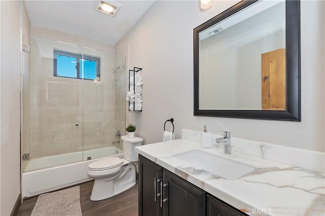 full bathroom featuring shower / bath combination with glass door, toilet, vanity, and hardwood / wood-style flooring