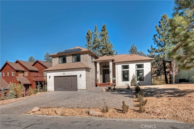 view of front of property featuring solar panels and a garage