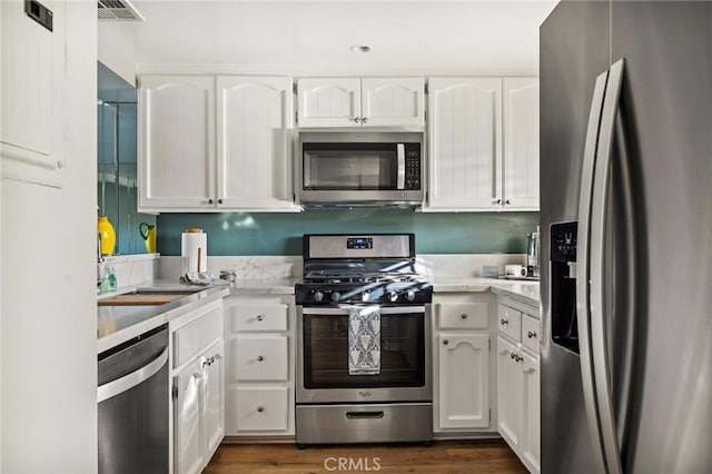 kitchen featuring white cabinets, stainless steel appliances, and dark wood-type flooring