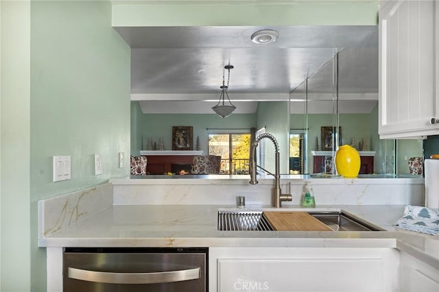 kitchen featuring dishwasher, a fireplace, white cabinetry, and sink