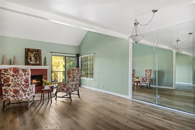 living area featuring vaulted ceiling with beams, a fireplace, and wood-type flooring